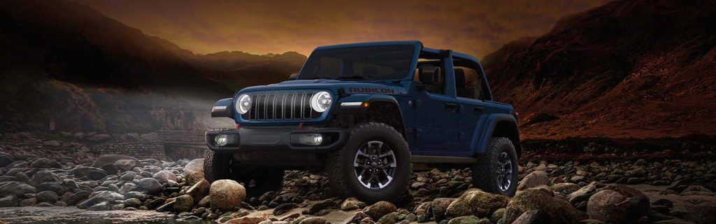 Blue Jeep Gladiator off-roading on rocky terrain at sunset.