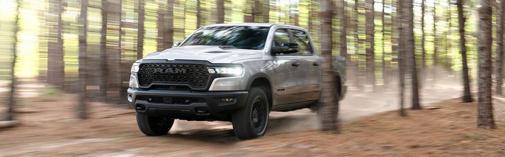 Silver RAM 1500 driving through a forest trail