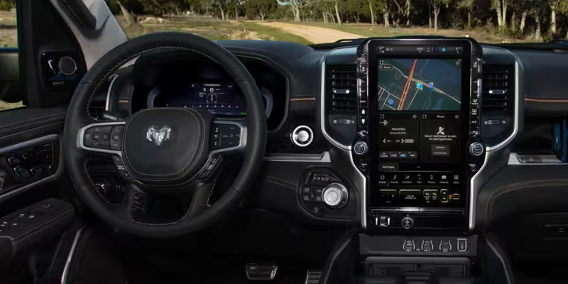 Interior of a RAM truck showing steering wheel, digital dashboard, and central touchscreen navigation display