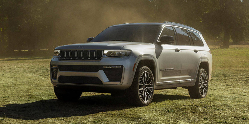 Silver Jeep Grand Cherokee SUV parked on a grassy field in an outdoor setting
