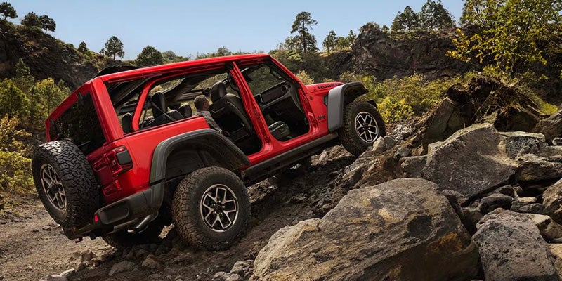 a red Jeep Wrangler climbing rocks